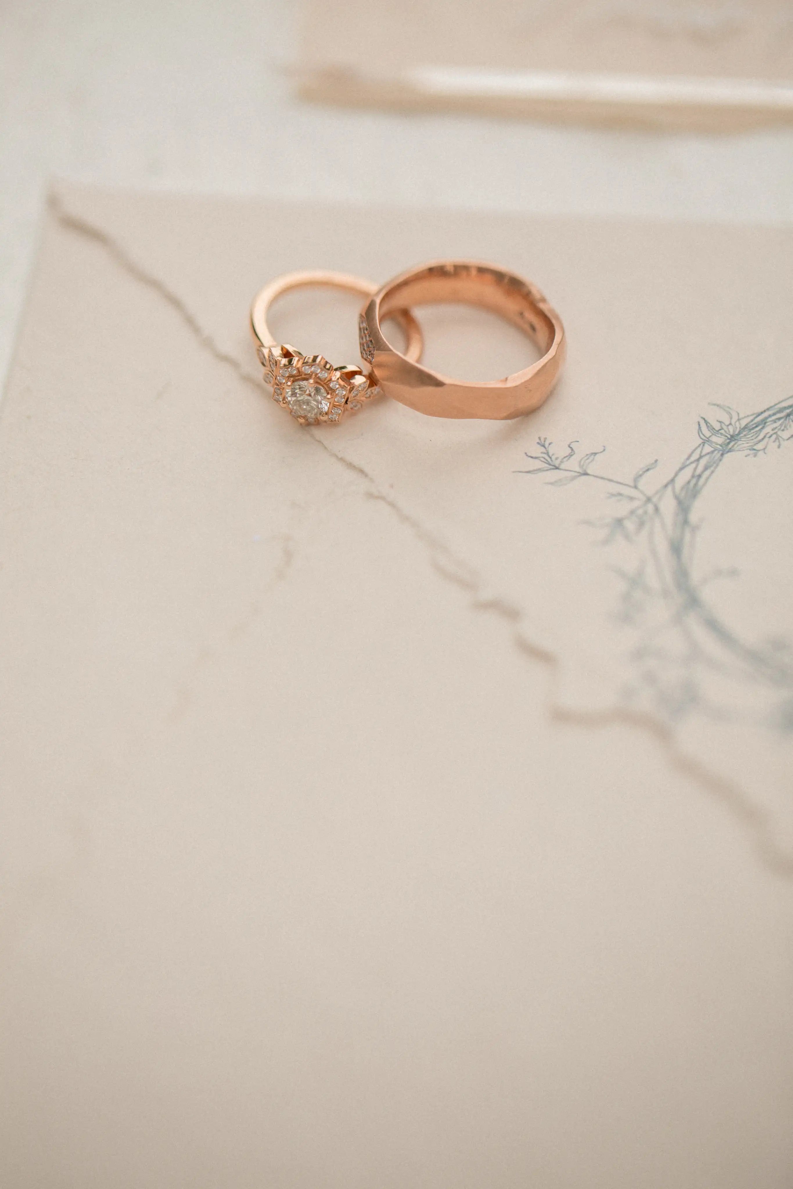 Two rose gold rings on a textured beige surface